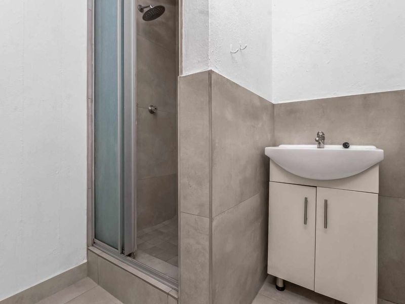 A compact bathroom featuring a shower enclosure with a modern shower head and a vanity unit with an integrated washbasin.