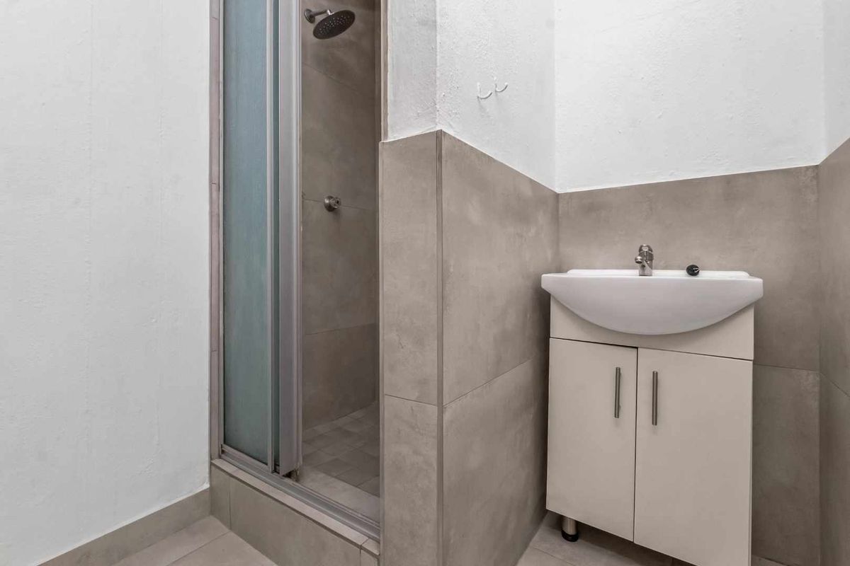 A compact bathroom featuring a shower enclosure with a modern shower head and a vanity unit with an integrated washbasin.