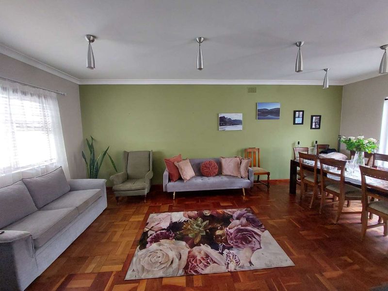 Spacious open-plan living and dining area featuring classic parquet flooring, neutral wall tones, and modern pendant lighting.