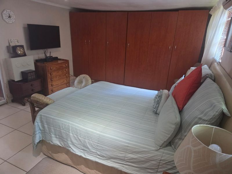 A bedroom featuring built-in wooden cupboards and tiled flooring, providing functional storage space within the cottage.
