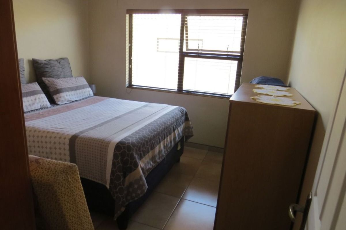 A standard bedroom featuring tiled flooring and a window with fitted blinds, providing natural light.