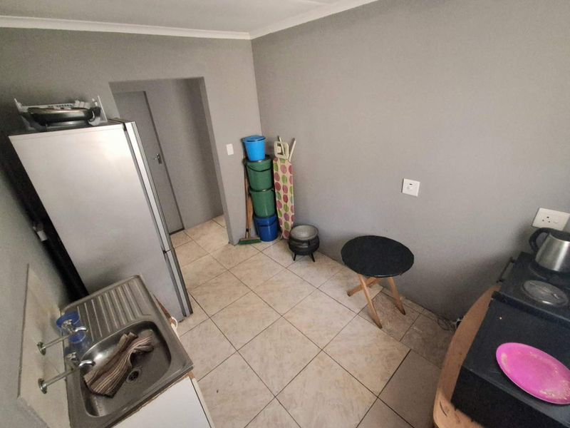 A functional kitchen area featuring tiled flooring, a stainless steel sink, and neutral wall finishes, providing a practical space for daily culinary tasks.