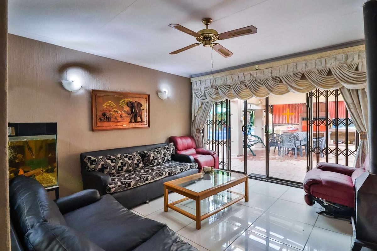 A living room featuring tiled flooring, a ceiling fan, and sliding glass doors that provide access to an outdoor patio area.