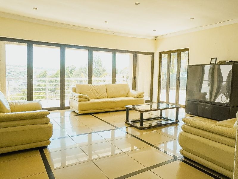 Spacious living room featuring large aluminium sliding doors that provide ample natural light and access to the outdoor area, complemented by tiled flooring.