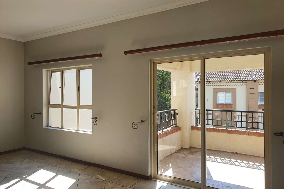 An empty living room featuring tiled flooring, coved ceilings, and a sliding glass door providing access to a private balcony.