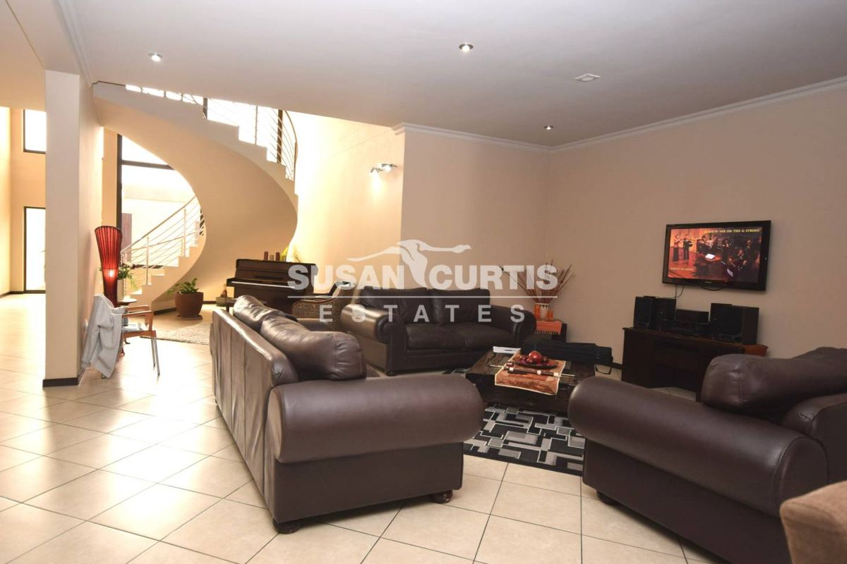 Spacious living area featuring a prominent curved staircase with metal balustrades and tiled flooring throughout.