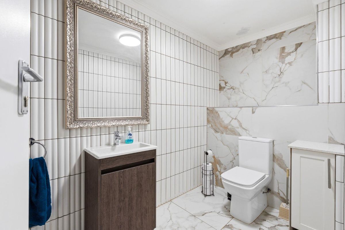 Modern bathroom featuring marble-look floor and wall tiles, a contemporary vanity with integrated basin, and a sleek toilet suite.