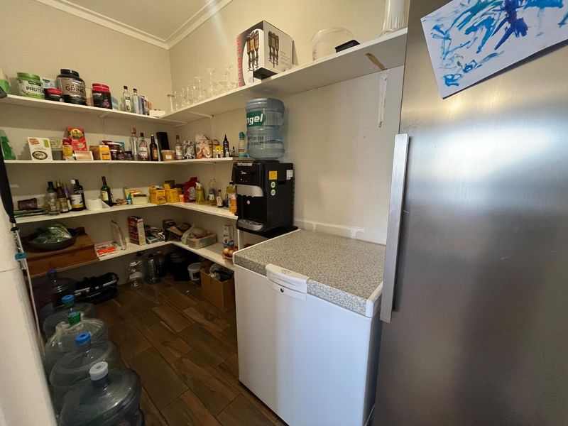 A functional scullery or pantry area featuring extensive built-in shelving and durable tiled flooring, providing ample storage space for household supplies.