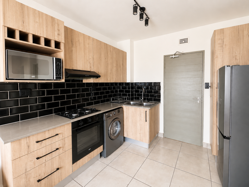 Modern kitchen featuring light wood cabinetry, black subway tile backsplash, integrated appliances, gas hob, and tiled flooring.
