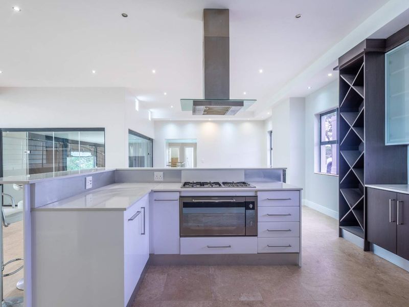 Modern kitchen featuring stone countertops, built-in gas hob, stainless steel extractor fan, and integrated wine storage cabinetry.
