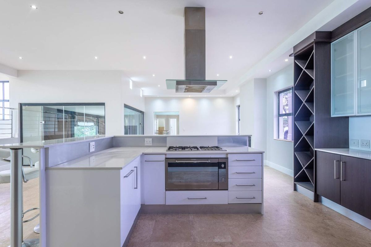 Modern kitchen featuring stone countertops, built-in gas hob, stainless steel extractor fan, and integrated wine storage cabinetry.