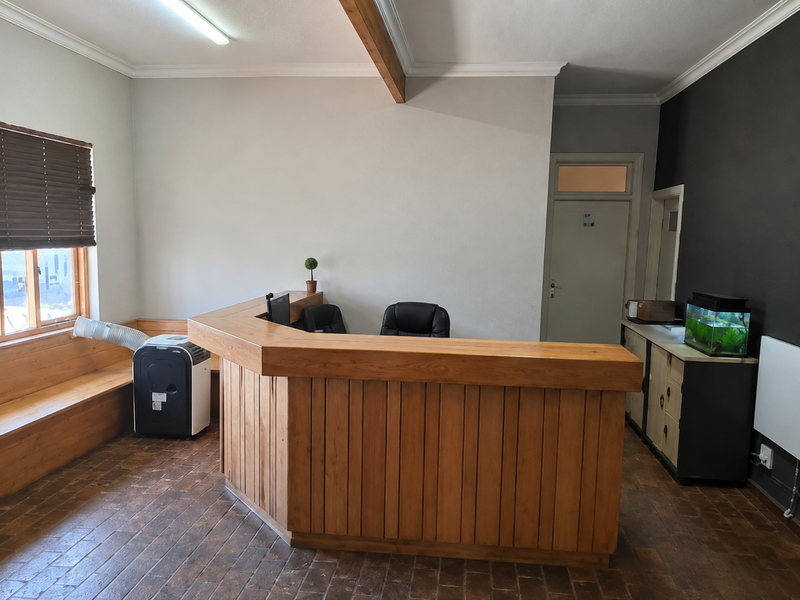 A functional office reception area featuring a large built-in wooden desk, integrated bench seating, and tiled flooring.