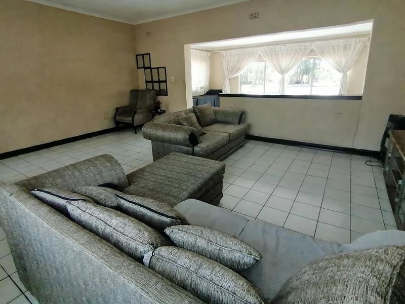 Spacious living room featuring neutral tiled flooring and a large window, offering a blank canvas for modern interior design updates.