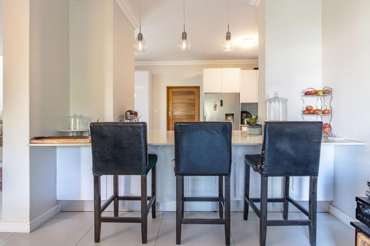 A modern kitchen featuring a central island with stone countertops, pendant lighting, and clean white cabinetry, creating a functional and bright cooking space.