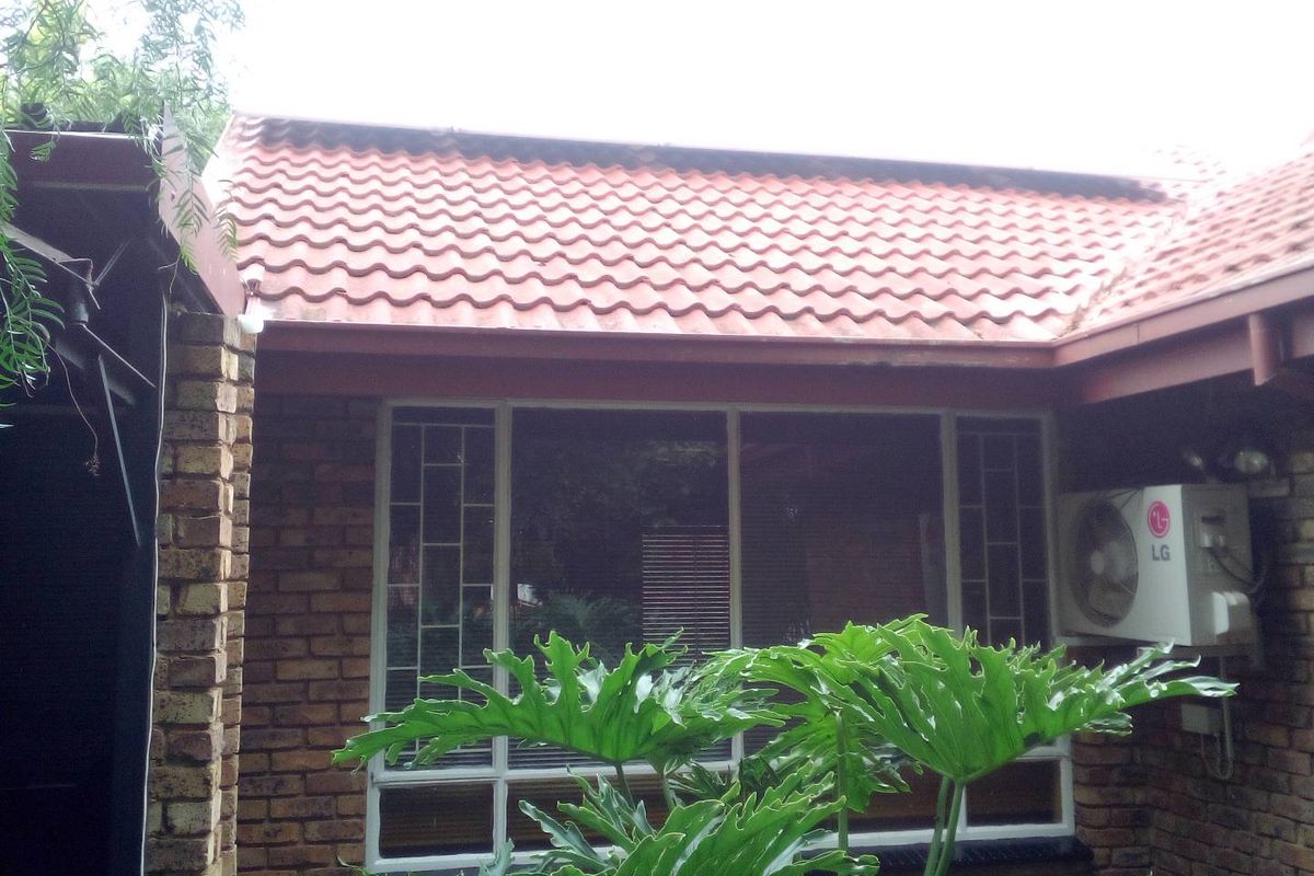 A view of the rear exterior facade featuring face-brick walls, terracotta-style roof tiles, and a wall-mounted air conditioning unit.