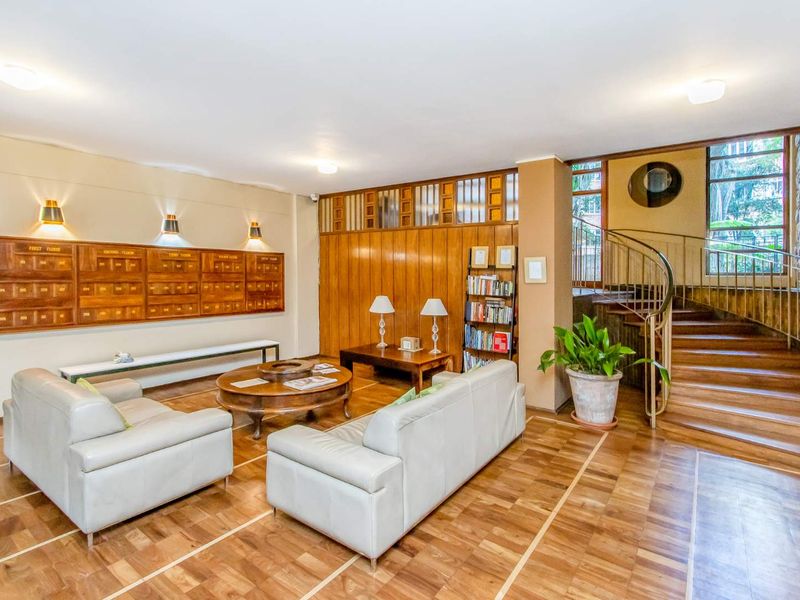 Elegant apartment building entrance lobby featuring warm wood parquet flooring, a classic spiral staircase, and integrated wooden mailboxes.