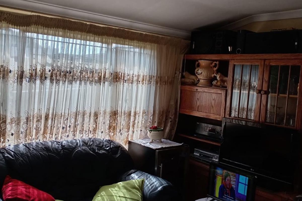 A cozy living room featuring a large window with sheer curtains and a built-in wooden display cabinet.