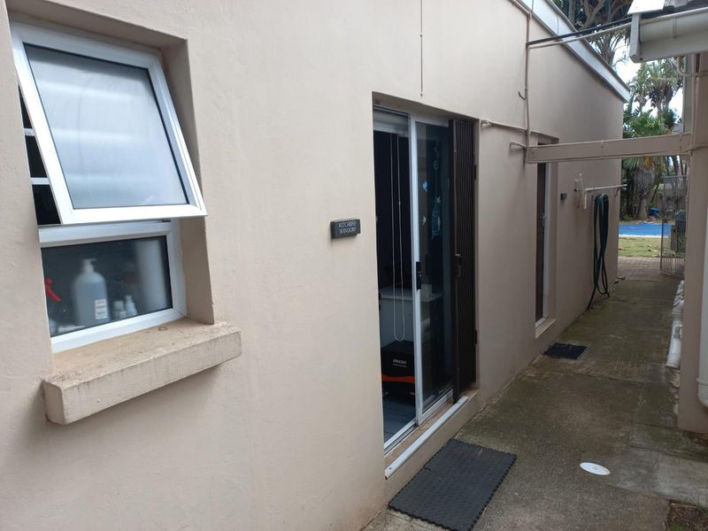 A view of the rear exterior pathway featuring a sliding glass door and an awning window, providing access to the side of the apartment.