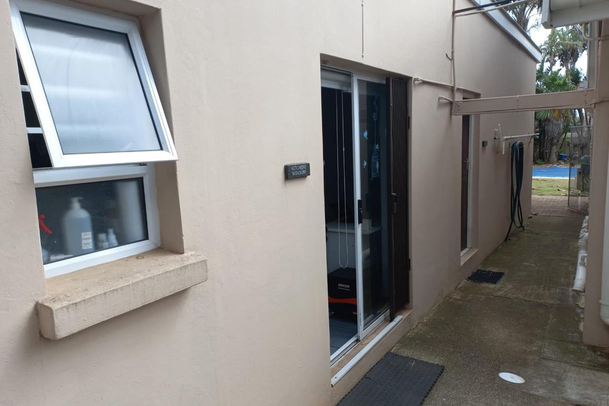 A view of the rear exterior pathway featuring a sliding glass door and an awning window, providing access to the side of the apartment.
