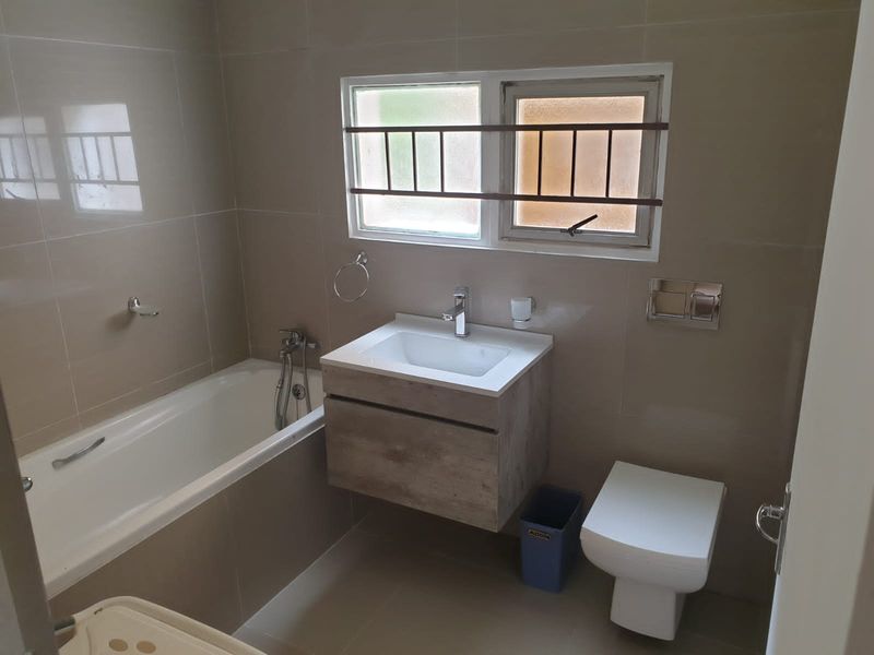 Modern bathroom featuring a wall-mounted vanity, wall-hung toilet with concealed cistern, and a built-in bathtub with tiled wall finishes.
