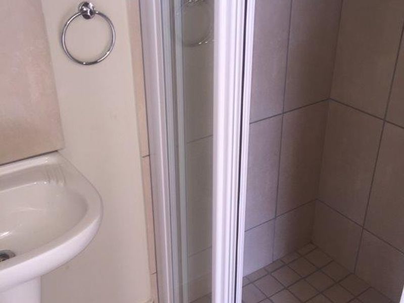 A functional bathroom featuring a pedestal basin and a tiled shower enclosure with a glass door.