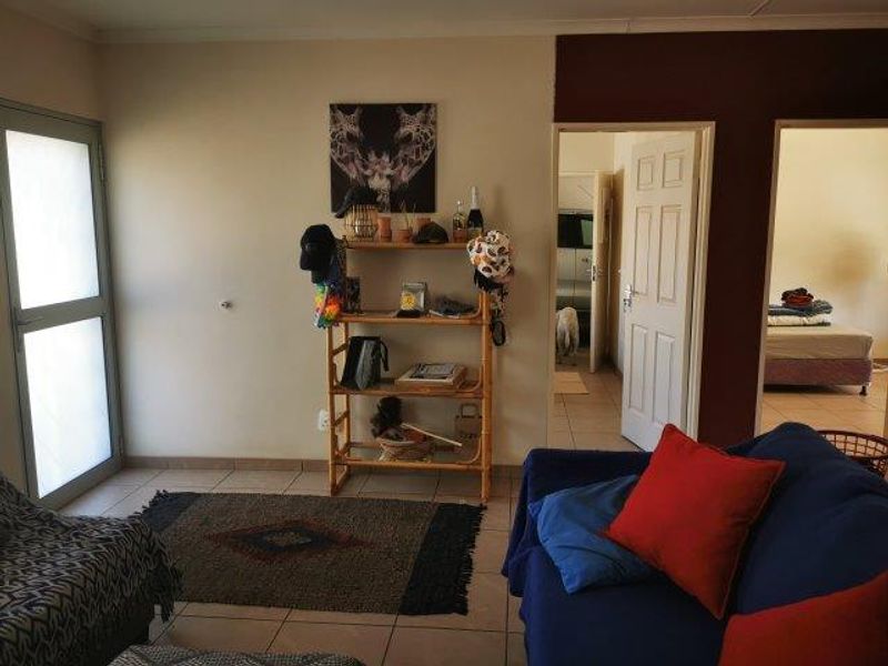 A living room area featuring tiled flooring and access to adjacent rooms through standard internal doors.