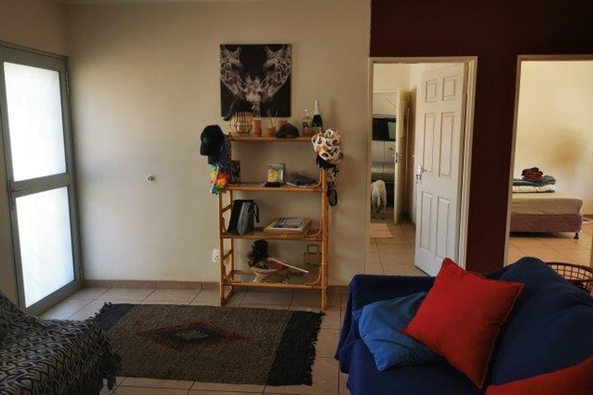 A living room area featuring tiled flooring and access to adjacent rooms through standard internal doors.