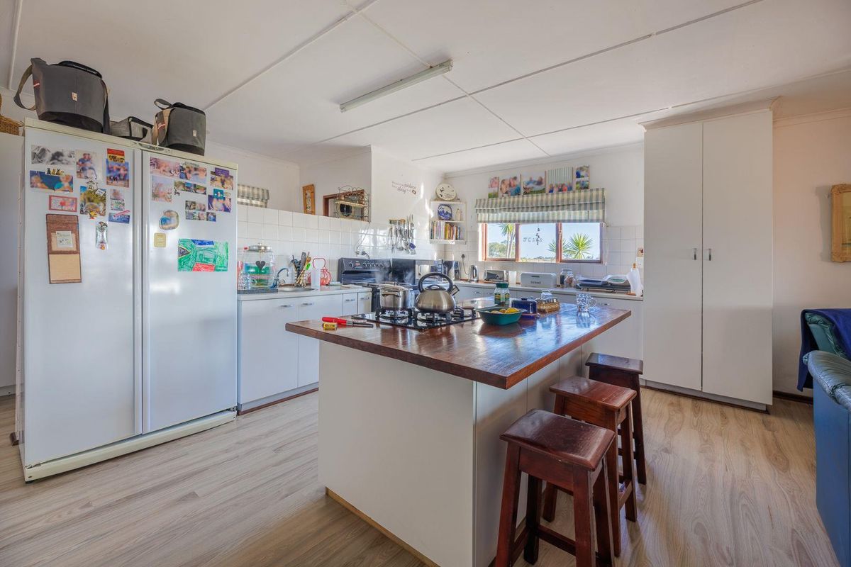 A functional kitchen featuring a central island with a wooden countertop, built-in cabinetry, and tiled splashbacks, offering a practical layout for daily meal preparation.