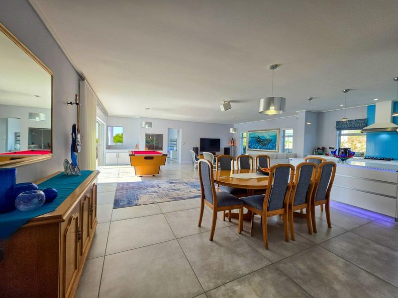Spacious open-plan living, dining, and kitchen area featuring large format floor tiles, modern cabinetry, and seamless flow to the outdoor patio.