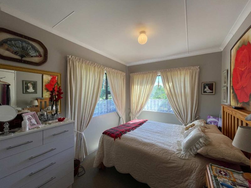 A cozy bedroom featuring neutral wall tones, dual windows with curtains, and standard ceiling finishes.
