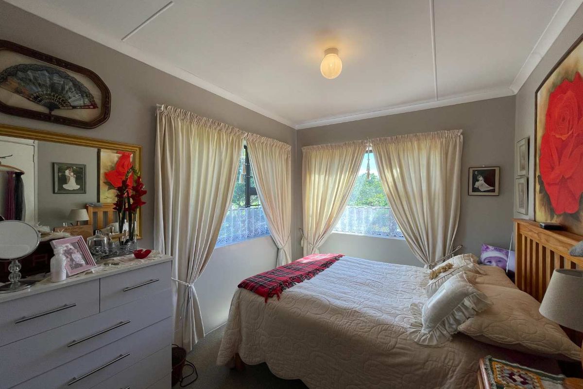 A cozy bedroom featuring neutral wall tones, dual windows with curtains, and standard ceiling finishes.