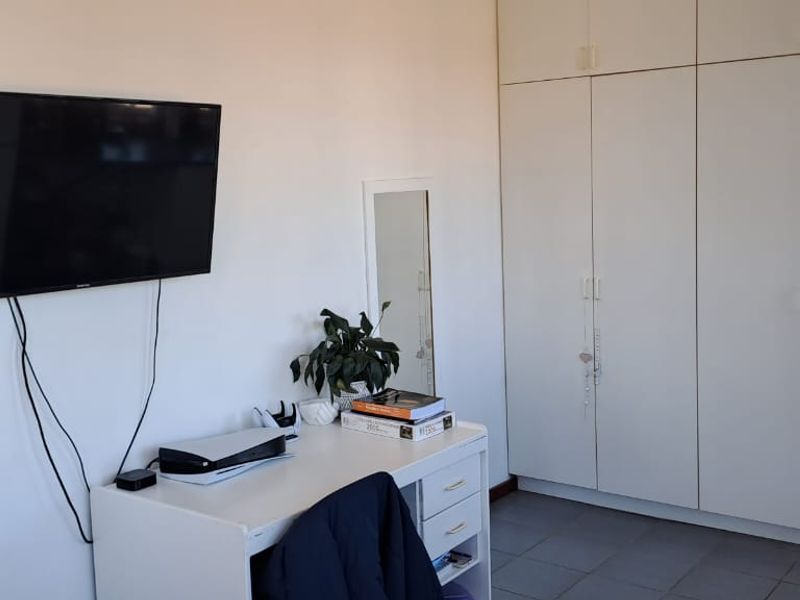 Bedroom featuring built-in wardrobes, tiled flooring, and direct access to the exterior via a timber door.