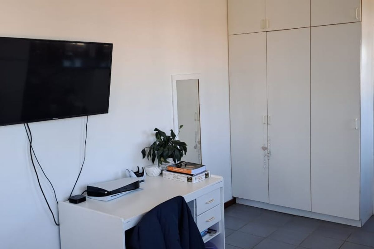 Bedroom featuring built-in wardrobes, tiled flooring, and direct access to the exterior via a timber door.
