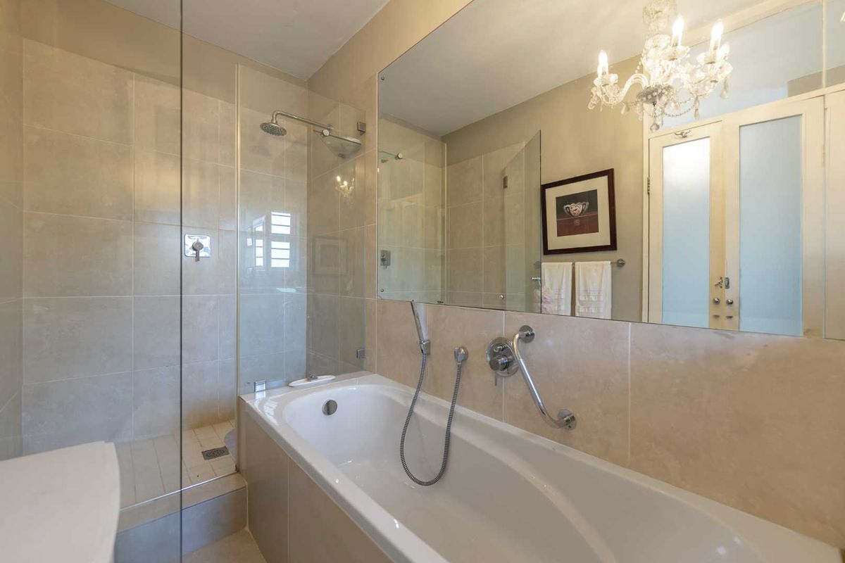 Modern bathroom featuring a built-in bathtub, separate glass-enclosed shower, and a large wall-mounted mirror with neutral tiling throughout.