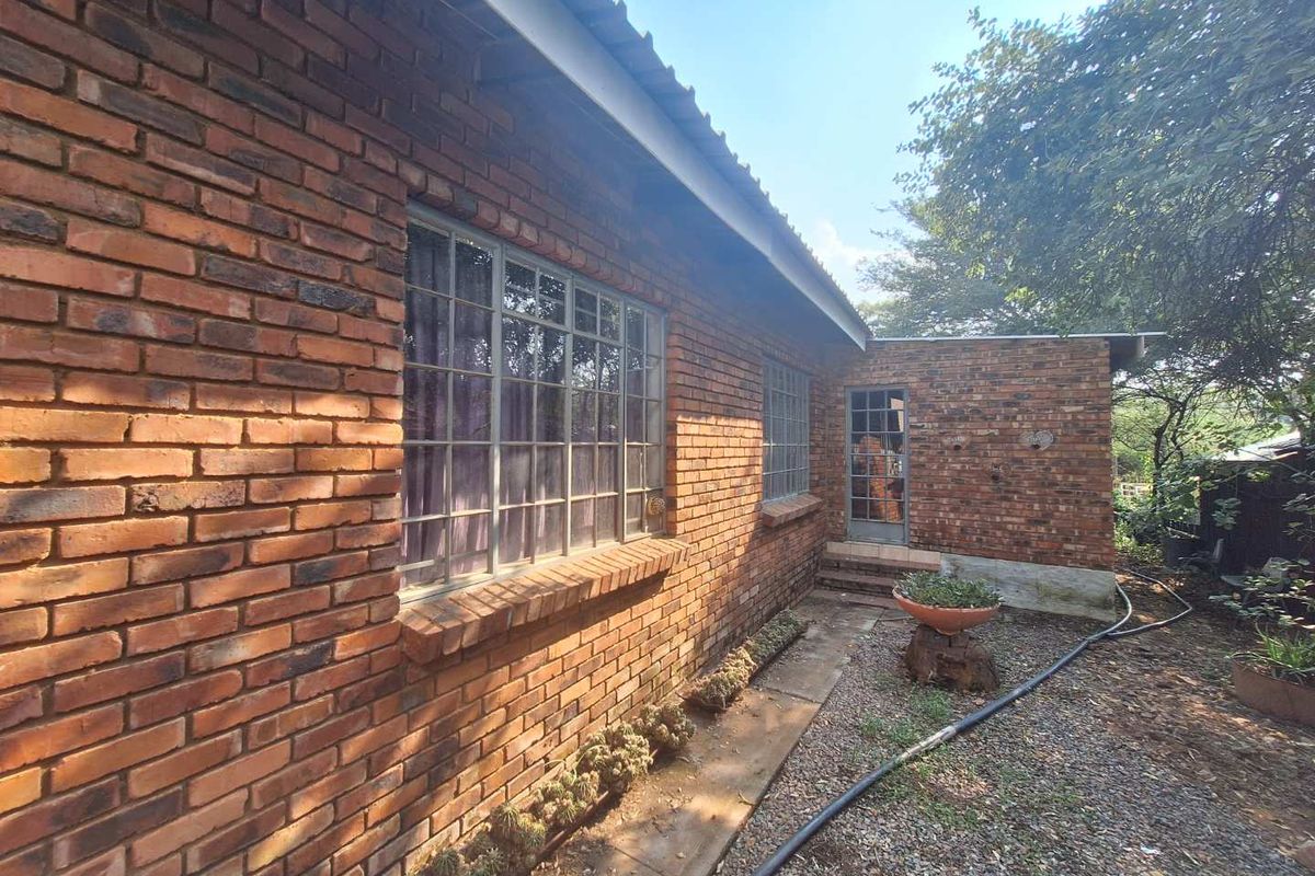 A view of the rear exterior brick facade featuring classic steel-framed windows and a paved walkway along the side of the house.