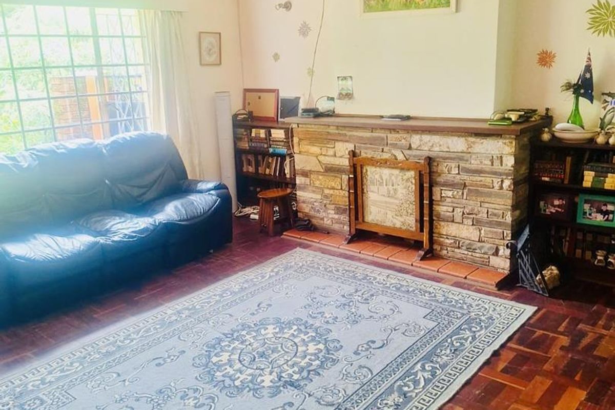 A cozy living room featuring a stone-clad fireplace, parquet flooring, and a wall-mounted air conditioning unit.