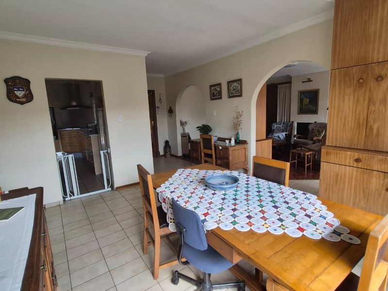 Dining room featuring tiled flooring, built-in wooden cabinetry, and an open-plan layout with archways leading to adjacent living and kitchen areas.
