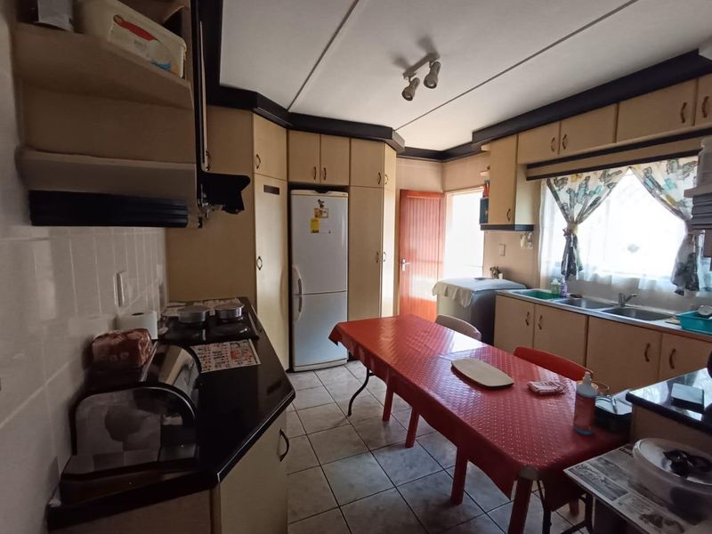 A functional kitchen featuring dated built-in cabinetry, laminate countertops, a double sink, and tiled flooring, offering potential for modern renovation.
