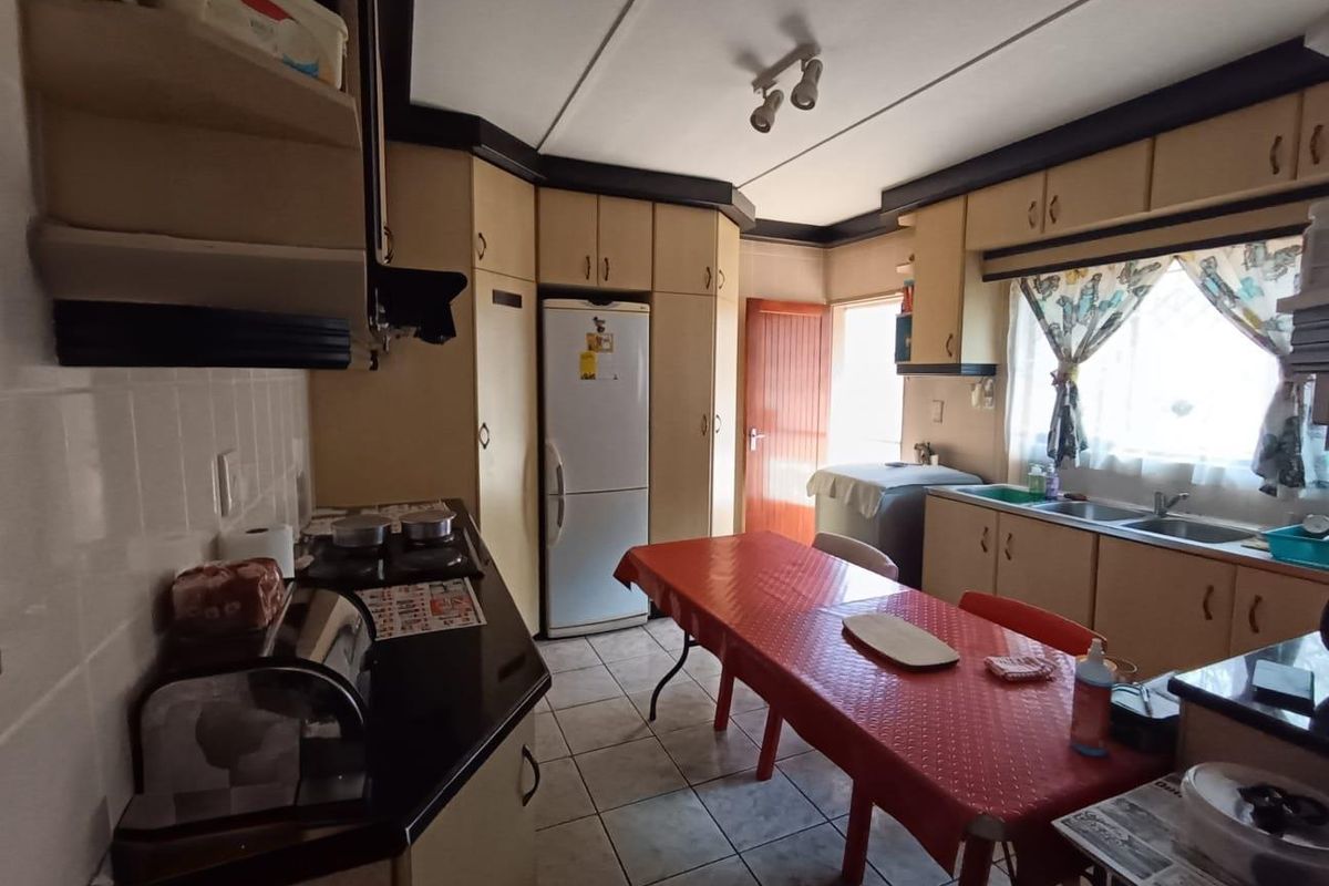 A functional kitchen featuring dated built-in cabinetry, laminate countertops, a double sink, and tiled flooring, offering potential for modern renovation.