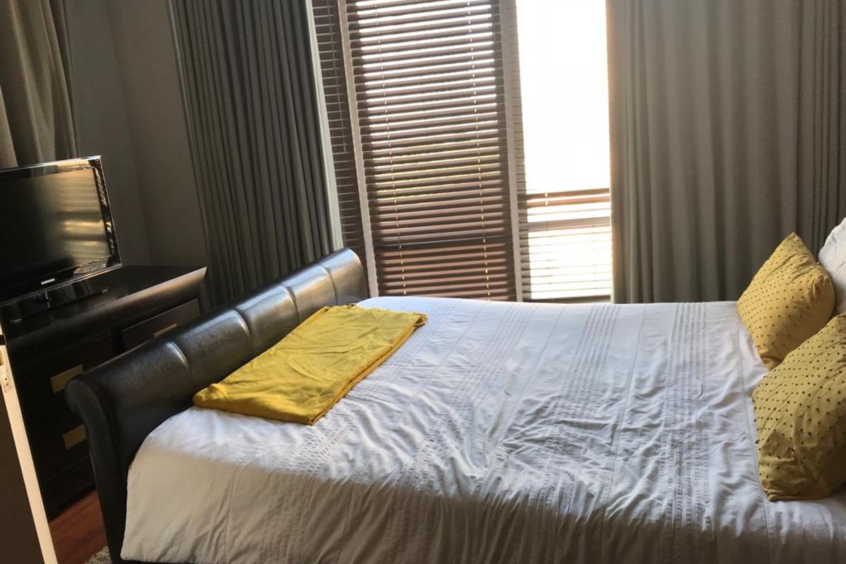 A well-lit bedroom featuring large windows with fitted blinds and floor-to-ceiling curtains, providing ample natural light and a comfortable living space.