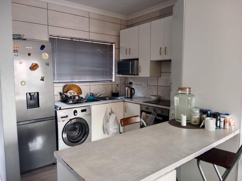 Compact kitchen featuring built-in cabinetry, laminate countertops, a tiled backsplash, and integrated cooking appliances, providing a functional workspace.