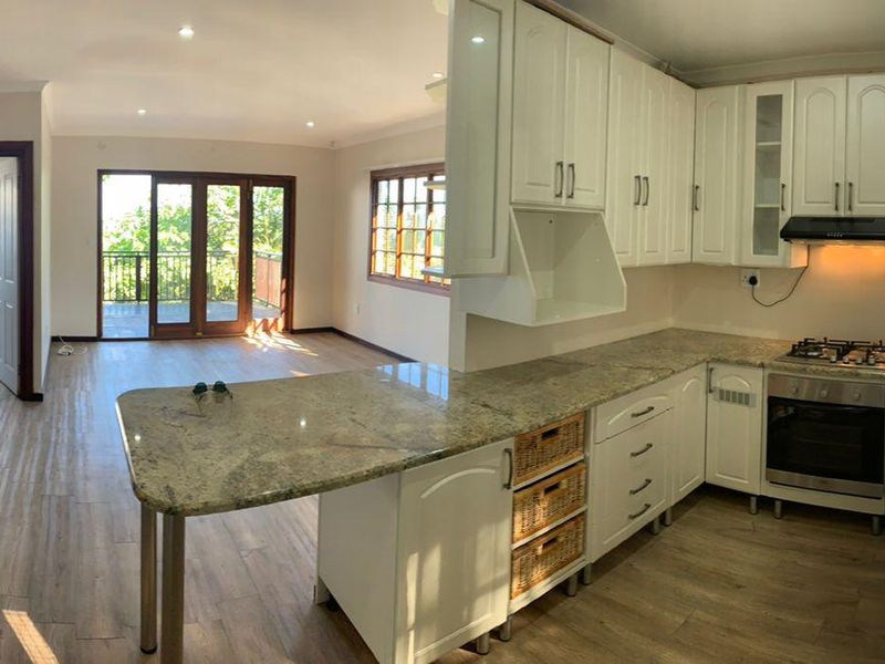 Spacious open-plan kitchen and living area featuring granite countertops, built-in cabinetry, and direct access to a balcony through sliding glass doors.