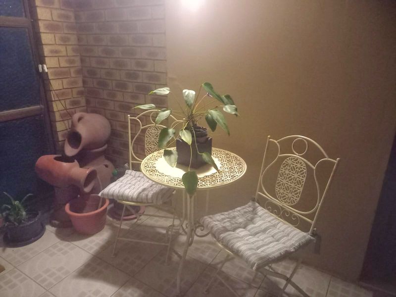 A covered patio area featuring exposed brickwork and tiled flooring, providing a cozy outdoor space for relaxation.