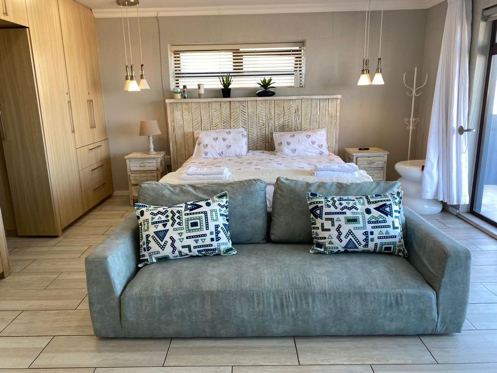 First-floor main bedroom with built-in cupboards and en-suite bathroom. It also has a balcony with distant sea views