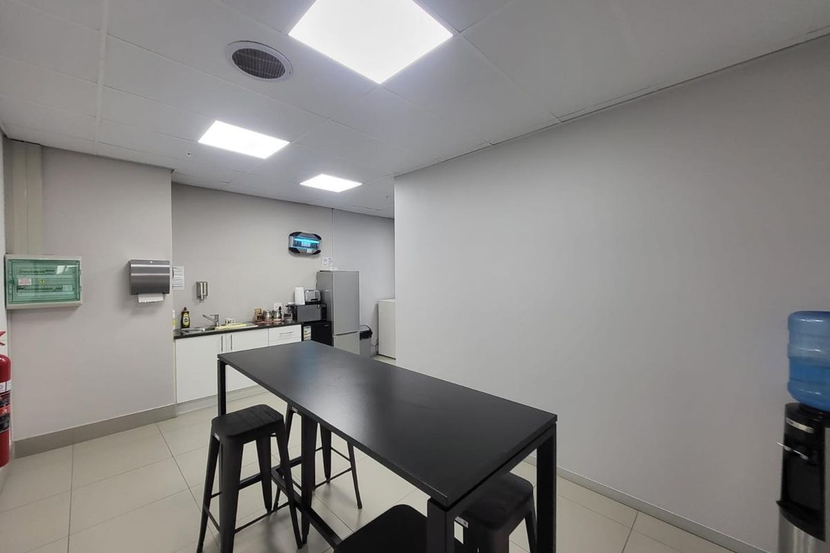 A functional industrial kitchenette area featuring built-in cabinetry, a sink, and a suspended ceiling with recessed lighting.