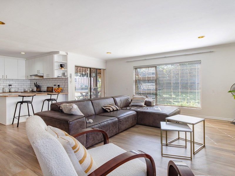 Spacious open-plan living area featuring a modern kitchen with subway tile backsplash, breakfast bar, and seamless flow to the lounge and outdoor access.