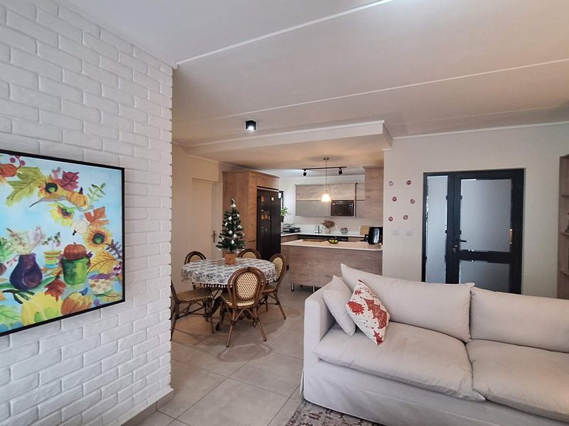 An open-plan living and kitchen area featuring a white brick feature wall, modern cabinetry, and tiled flooring, creating a bright and functional living space.