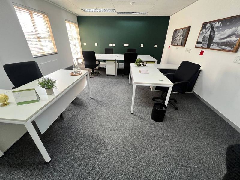 A well-maintained office space featuring carpeted flooring, recessed ceiling lighting, and large windows with venetian blinds, providing a professional work environment.