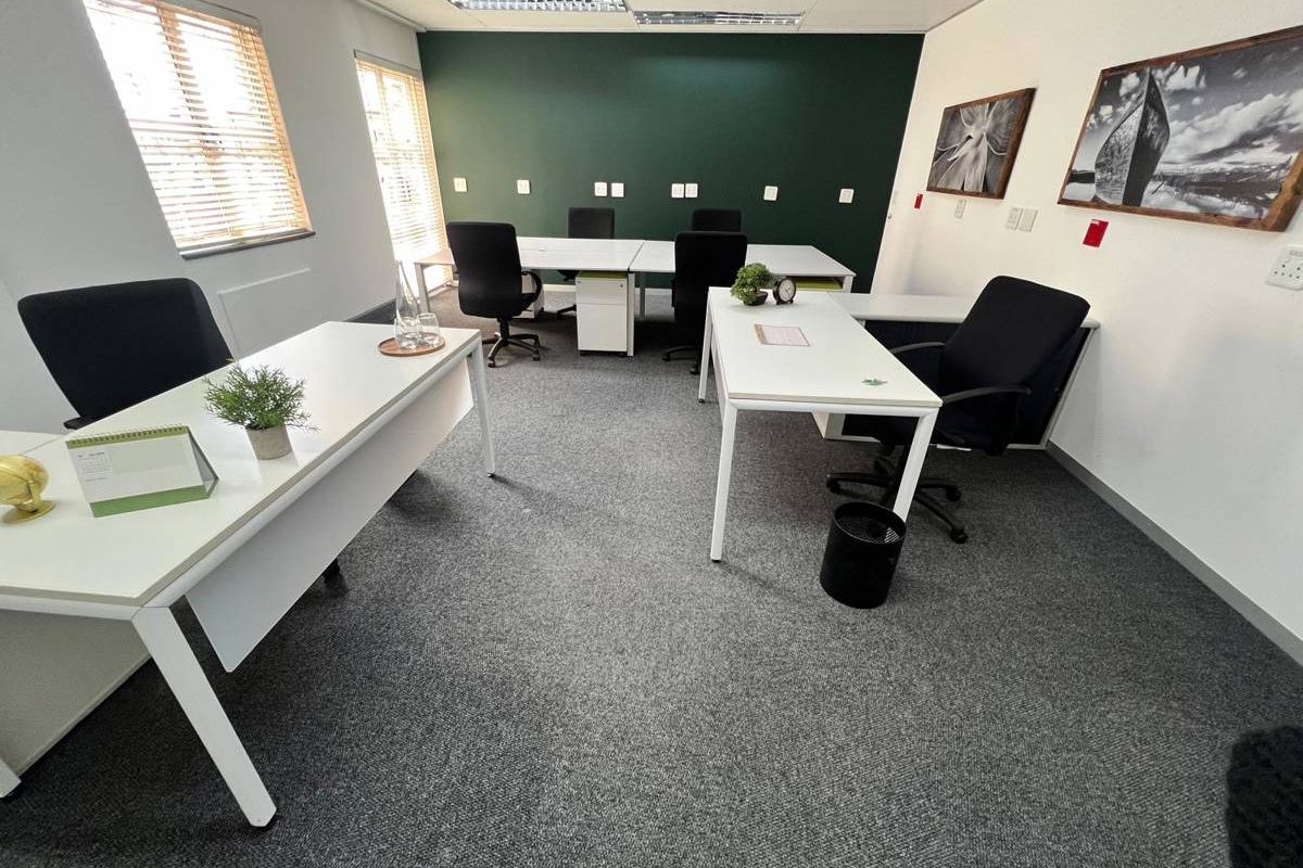 A well-maintained office space featuring carpeted flooring, recessed ceiling lighting, and large windows with venetian blinds, providing a professional work environment.