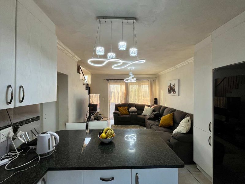 Open-plan living area featuring a kitchen island with granite countertops, tiled flooring, and a staircase leading to the upper level.